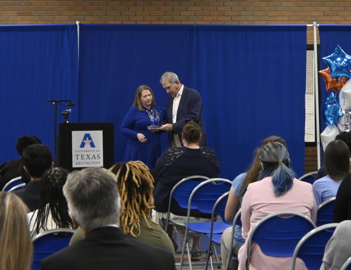 Dr. Charla Markham Shaw, chair of the University of Texas at Arlington Communication Department, and former UTA President James D. Spaniolo admire the award presented to Spaniolo for excellence in communication. The award ceremony was part of the Communication Department's annual Comm Day, when students have opportunities to network with communication professionals and learn more about the fields for which they are training. The department hosted Comm Day on Oct. 15.