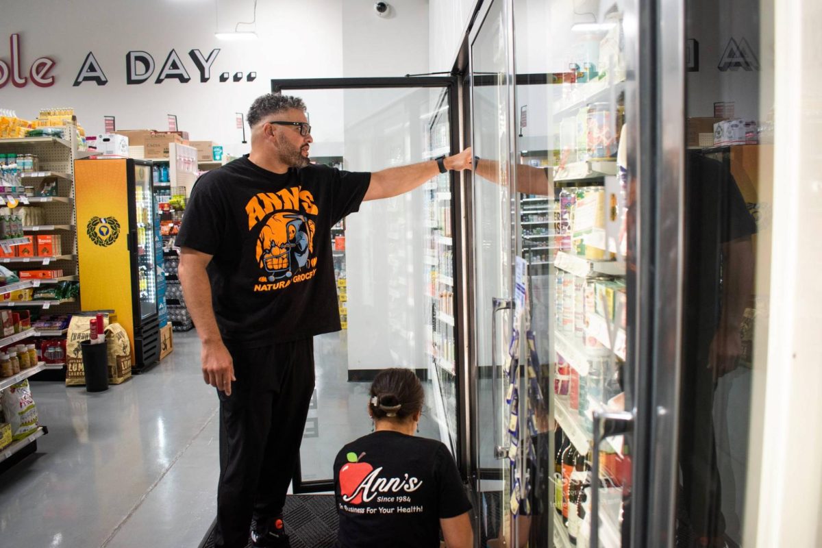 Ann's Natural Grocery & Nutrition managing partner Corey Houston helps Arlington resident and employee Mitzi Castaneda stock products. 