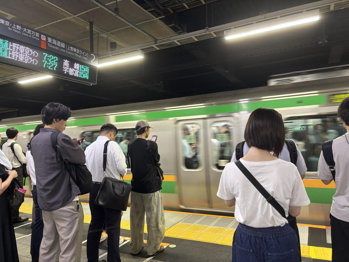Commuters wait patiently to board an arriving train in Tokyo.