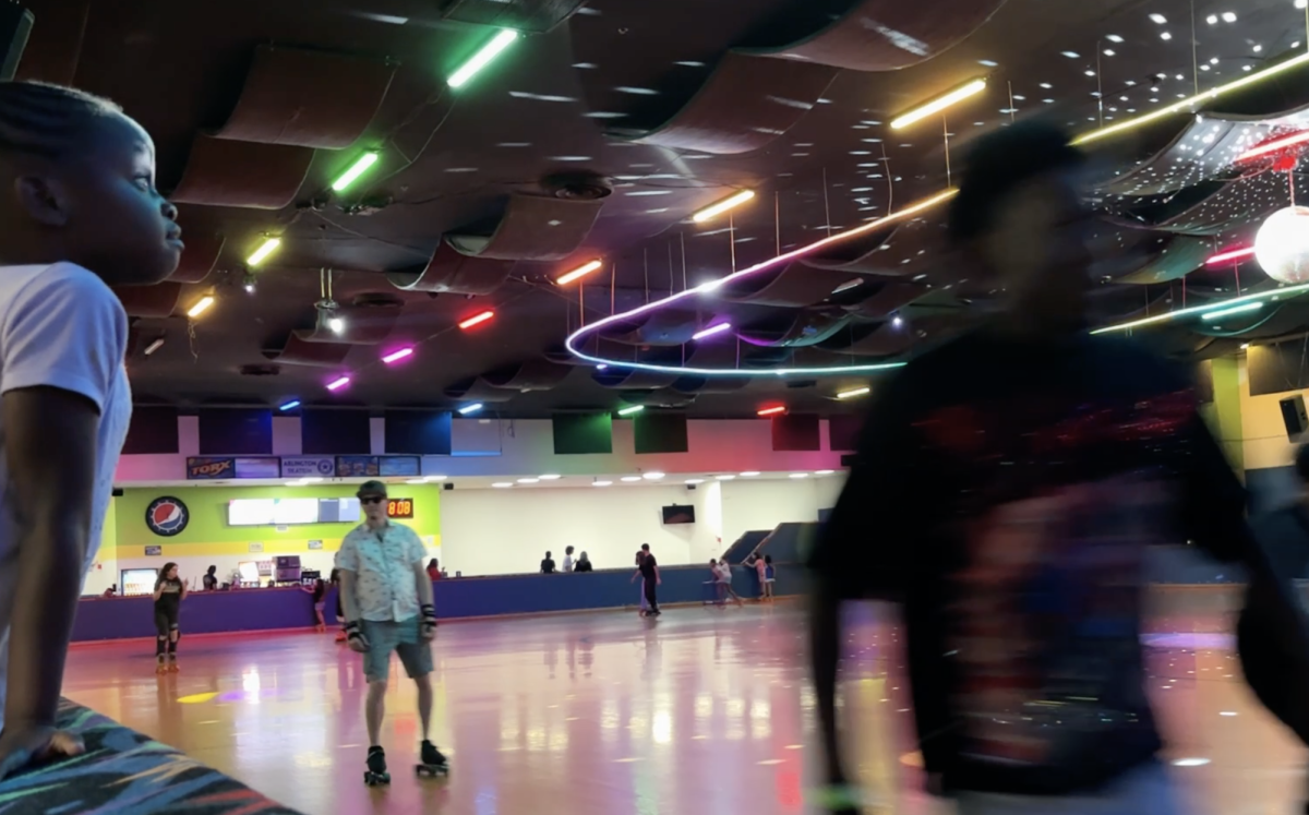 A young girl watches as skaters rush around the rink at Arlington Skatium.