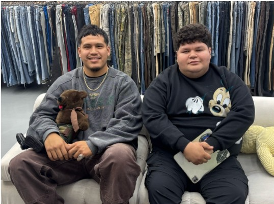 Carlos Vega, co-owner of Stash VHS, and Jonathan Cruz, sales associate, sit on a couch at the entrance of the store on Feb. 14, 2026.